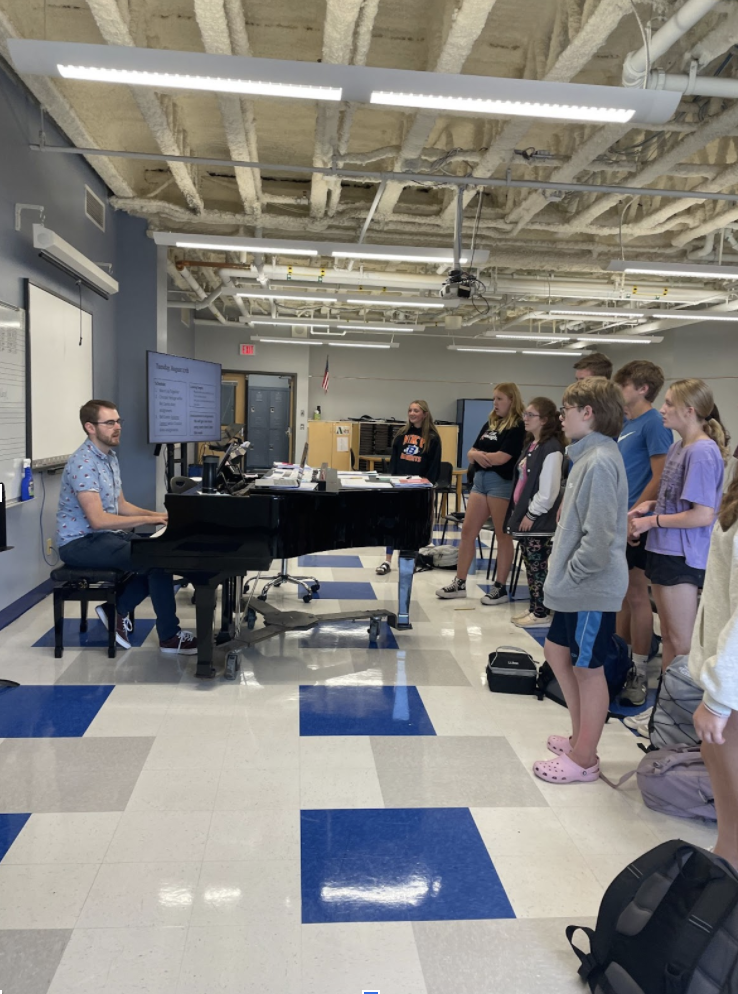 The choir warms up their vocals under the direction of Eaton.